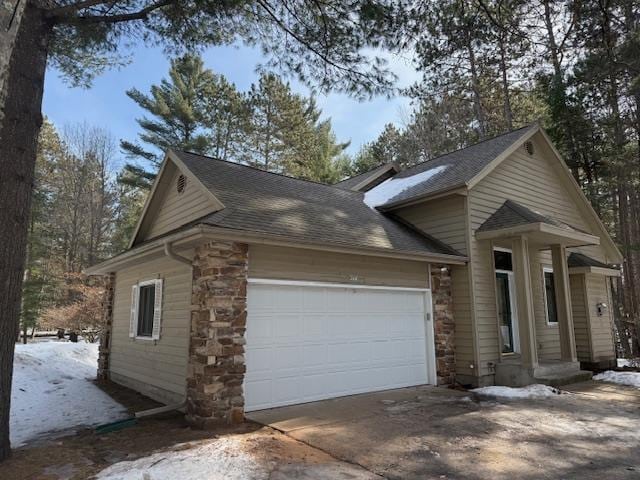 view of front of home featuring stone siding, an attached garage, concrete driveway, and roof with shingles