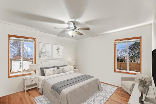 bedroom featuring light wood-type flooring, multiple windows, and a ceiling fan