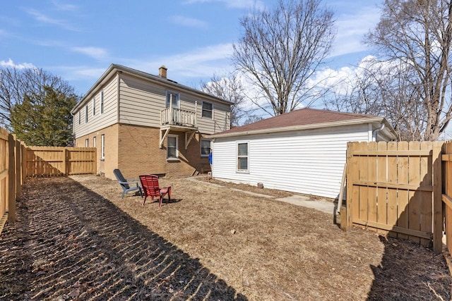 rear view of property featuring brick siding, a fenced backyard, a chimney, and a balcony