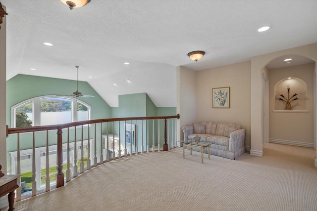 sitting room featuring a textured ceiling, vaulted ceiling, carpet, and ceiling fan