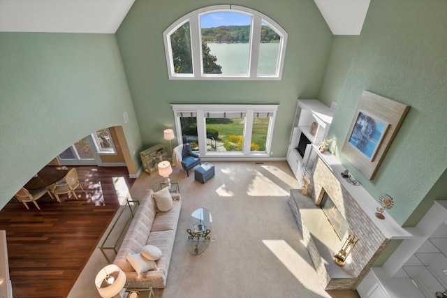 living room featuring a wealth of natural light, a glass covered fireplace, arched walkways, and high vaulted ceiling