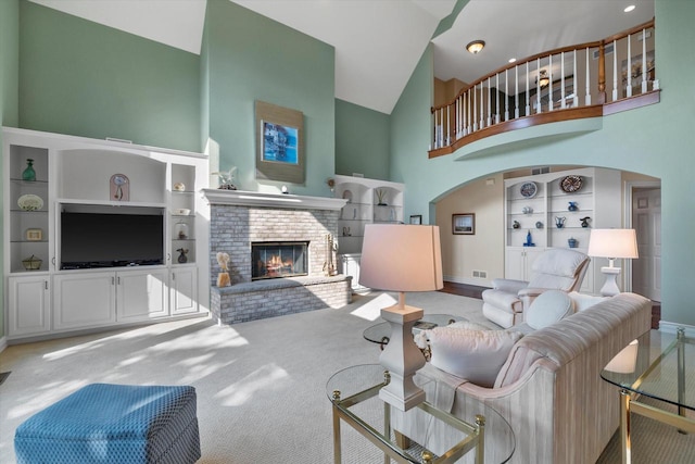 living room featuring built in shelves, baseboards, a fireplace, arched walkways, and high vaulted ceiling