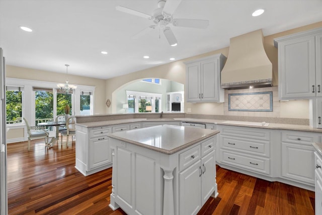 kitchen with white cabinets, a kitchen island, a healthy amount of sunlight, and custom range hood