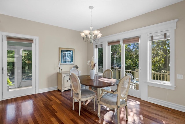 dining space featuring dark wood finished floors, visible vents, baseboards, and an inviting chandelier