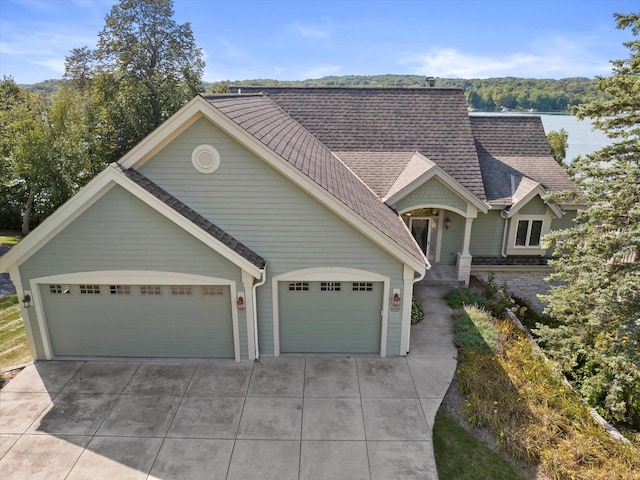 view of front of house with concrete driveway, an attached garage, and roof with shingles