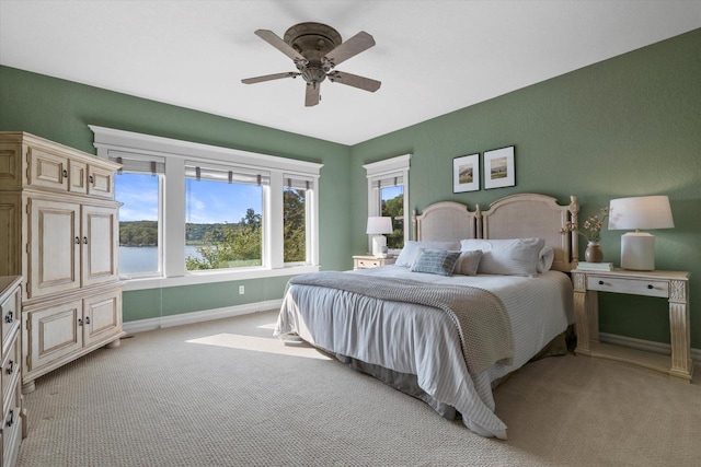 bedroom featuring light colored carpet, a ceiling fan, and baseboards