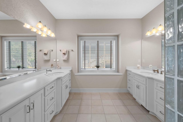 bathroom with tile patterned flooring, two vanities, baseboards, and a sink