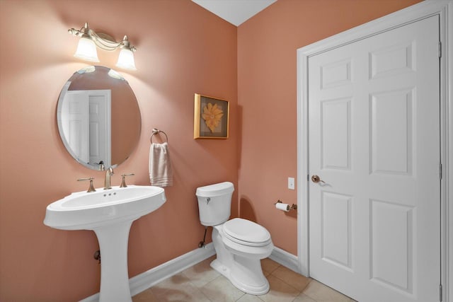 bathroom featuring a sink, baseboards, toilet, and tile patterned flooring