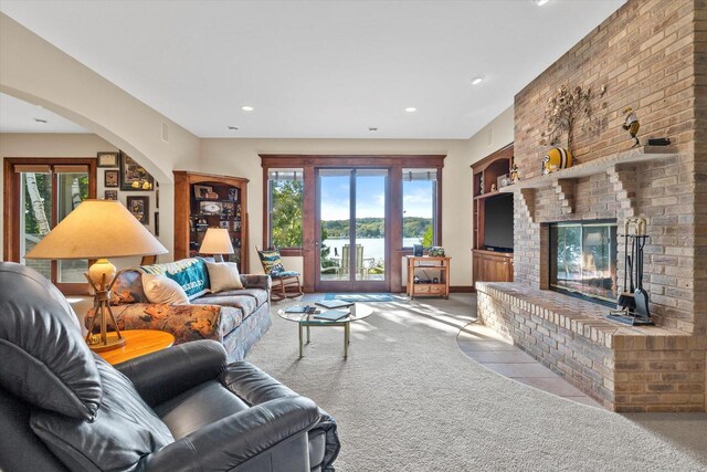 living room featuring arched walkways, recessed lighting, a brick fireplace, and carpet floors