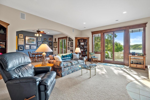 carpeted living area featuring tile patterned floors, visible vents, arched walkways, and recessed lighting