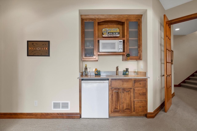 bar with stairway, white microwave, visible vents, refrigerator, and light colored carpet