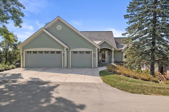 view of front of property with concrete driveway, an attached garage, and a shingled roof