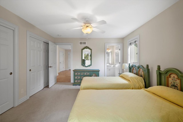 bedroom featuring visible vents, baseboards, light carpet, ensuite bath, and a ceiling fan