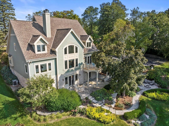 rear view of house featuring a patio, a balcony, cooling unit, a chimney, and a shingled roof