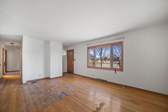 spare room featuring hardwood / wood-style floors, visible vents, and baseboards