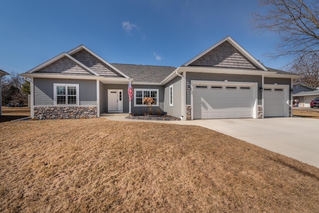 view of front of property with a front lawn, an attached garage, stone siding, and driveway