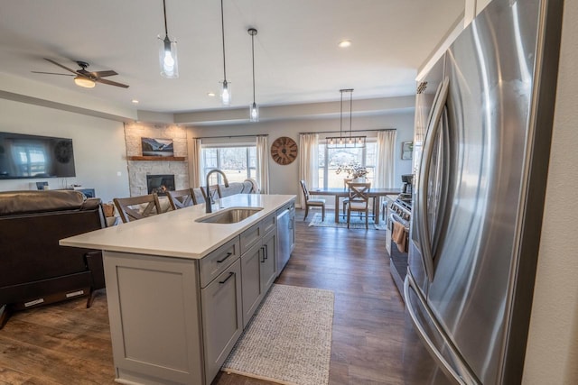 kitchen with a fireplace, a sink, gray cabinetry, stainless steel appliances, and open floor plan