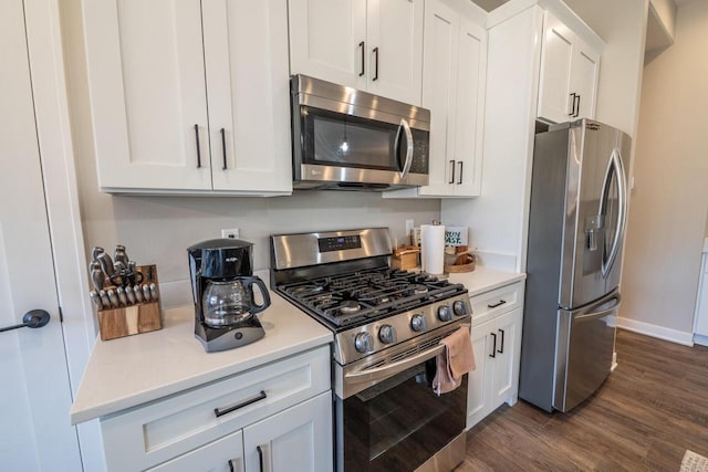 kitchen with dark wood-style floors, baseboards, stainless steel appliances, light countertops, and white cabinetry