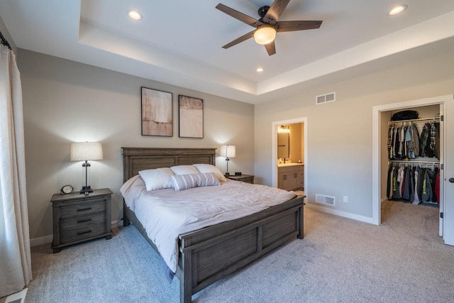 bedroom featuring visible vents, a walk in closet, recessed lighting, baseboards, and a raised ceiling