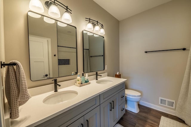 bathroom with a sink, visible vents, toilet, and wood finished floors