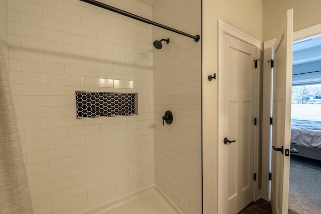 bathroom with connected bathroom and tiled shower