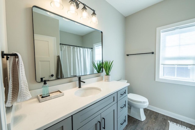 full bath featuring toilet, vanity, baseboards, and wood finished floors