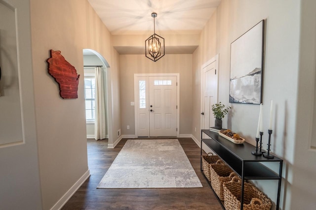 entryway featuring arched walkways, a chandelier, baseboards, and dark wood-style flooring