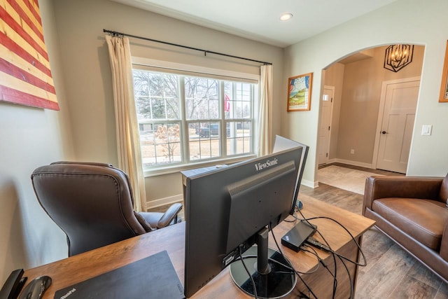 interior space with a chandelier, arched walkways, baseboards, and wood finished floors