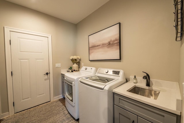 clothes washing area with a sink, cabinet space, and washer and clothes dryer