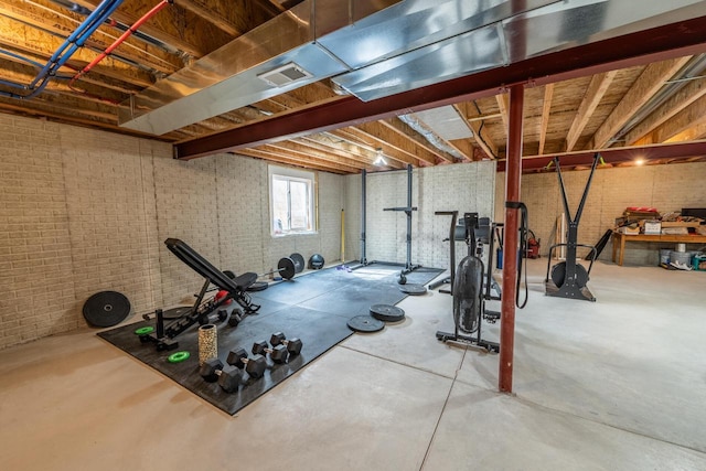 exercise room with visible vents and brick wall