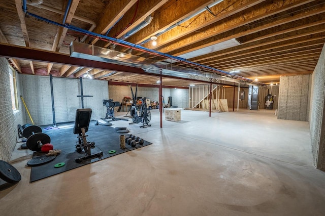 unfinished below grade area featuring water heater, brick wall, and stairs