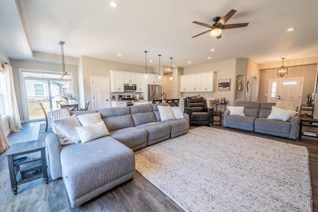 living area with recessed lighting, dark wood-style floors, and ceiling fan with notable chandelier