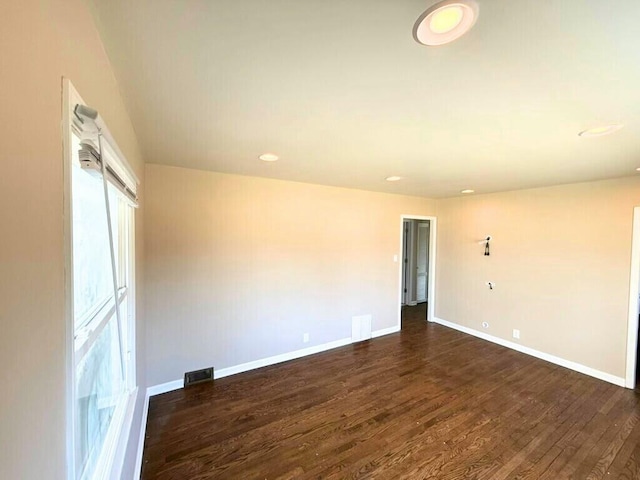 empty room featuring visible vents, baseboards, and dark wood-style flooring