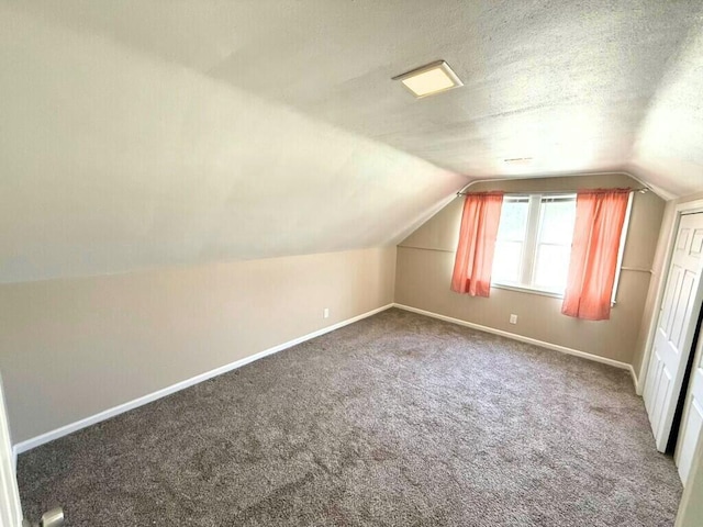 bonus room with a textured ceiling, carpet, baseboards, and vaulted ceiling