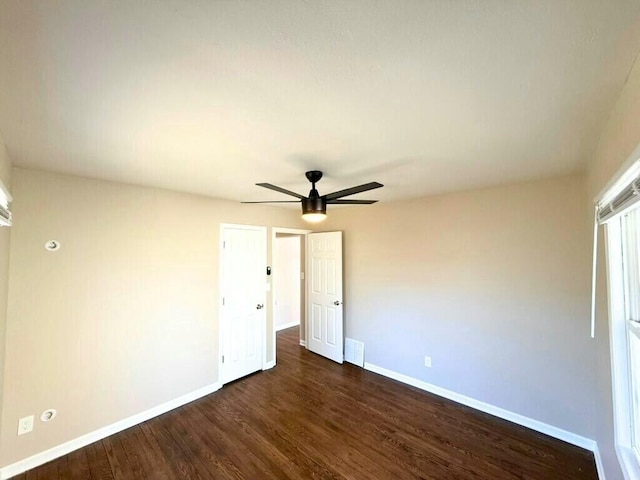 empty room with ceiling fan, visible vents, baseboards, and dark wood-style floors