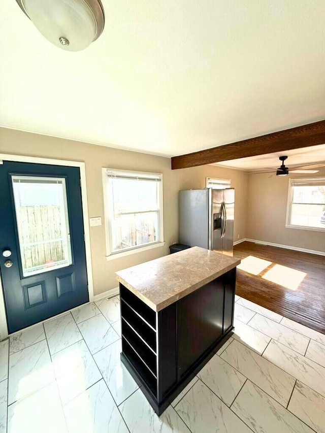 kitchen with marble finish floor, a kitchen island, baseboards, and stainless steel fridge with ice dispenser