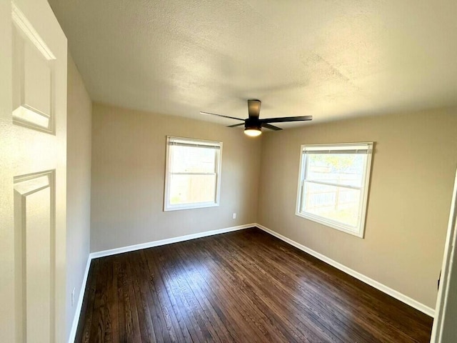 empty room with a healthy amount of sunlight, baseboards, and dark wood-style flooring