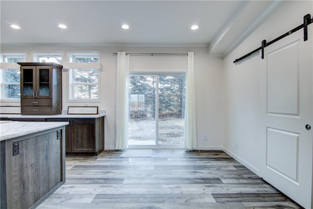 kitchen with a barn door, recessed lighting, and light wood finished floors