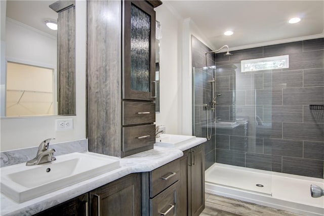 bathroom featuring a sink, a stall shower, double vanity, and crown molding