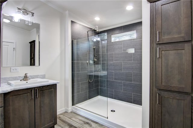 full bathroom featuring crown molding, baseboards, a stall shower, wood finished floors, and vanity