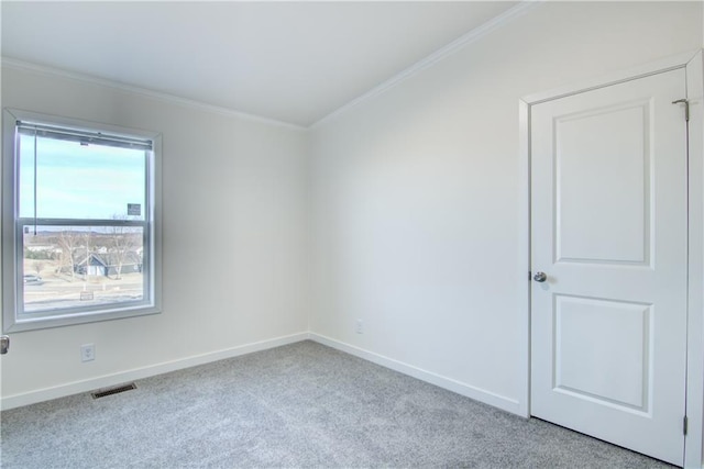 spare room with crown molding, carpet flooring, baseboards, and visible vents