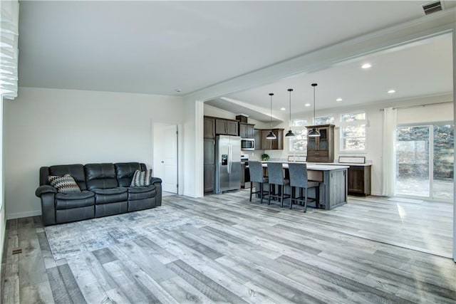 living room with lofted ceiling, recessed lighting, visible vents, and light wood-type flooring