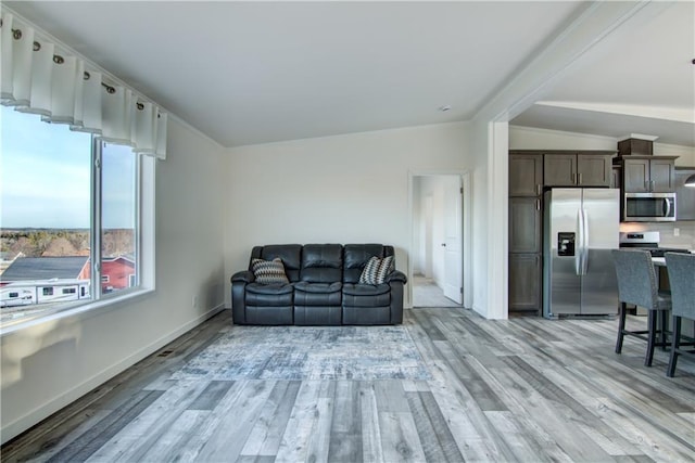 living room featuring lofted ceiling, crown molding, baseboards, and light wood finished floors