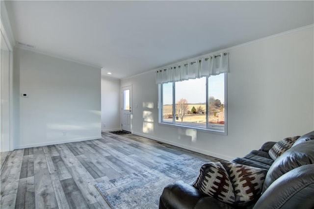 living area featuring baseboards, wood finished floors, and ornamental molding