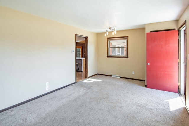 empty room featuring carpet, visible vents, and baseboards