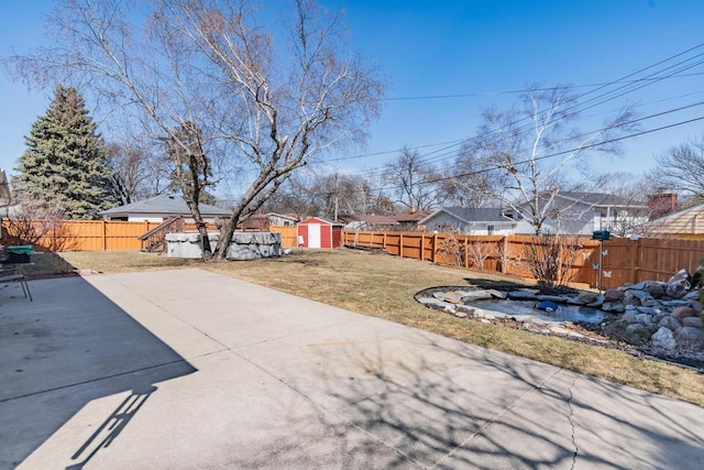 view of yard with a patio area, an outbuilding, a storage shed, and a fenced backyard