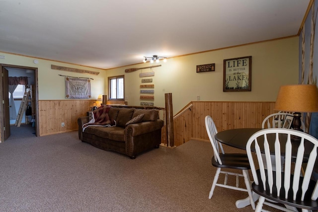 living area with crown molding, wooden walls, carpet flooring, and a wainscoted wall