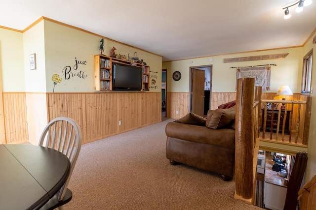 carpeted living area with a wainscoted wall, wood walls, and ornamental molding