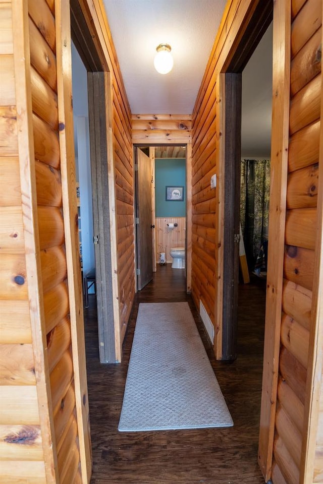 hallway with dark wood finished floors and rustic walls