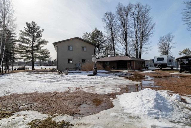 snow covered rear of property featuring a garage